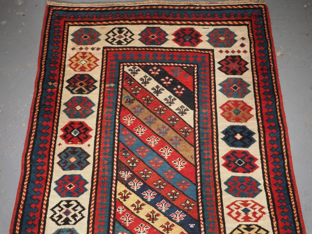 An antique Caucasian Gendje wool runner rug featuring a central field with diagonal stripes in red, blue, and cream surrounded by geometric borders. View II