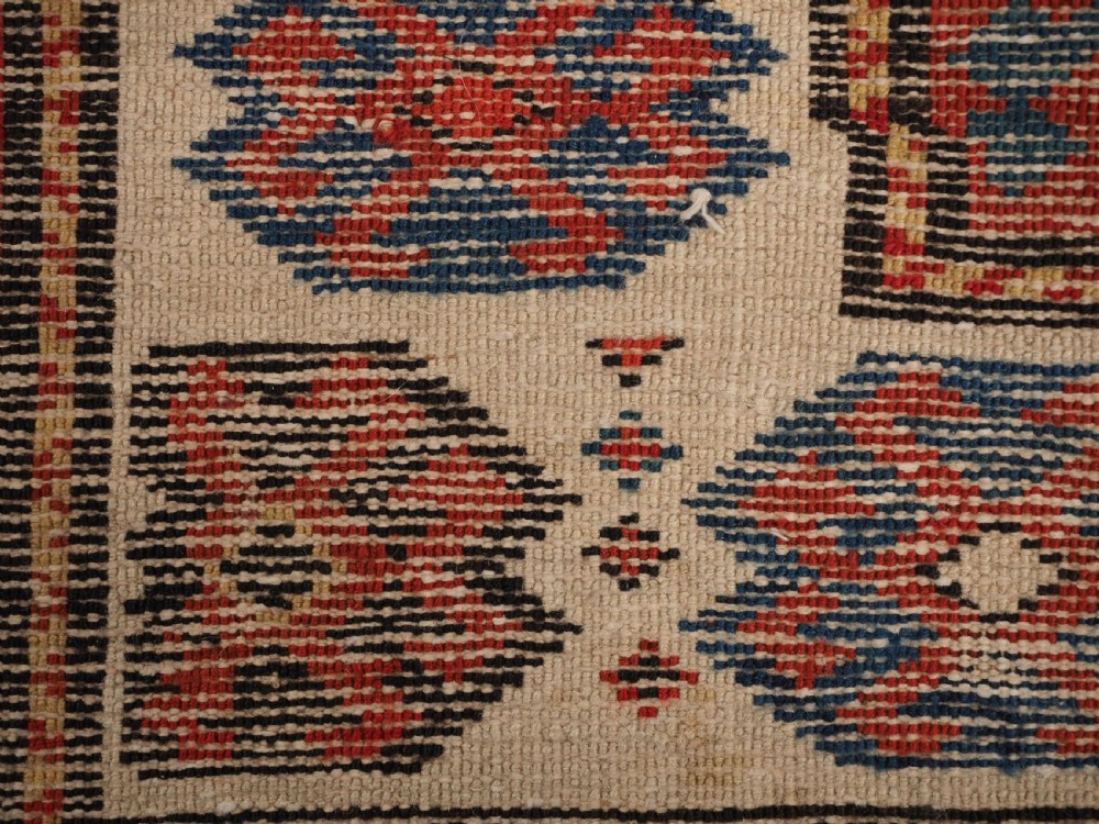 An antique Caucasian Gendje wool runner rug featuring a central field with diagonal stripes in red, blue, and cream surrounded by geometric borders. View IX