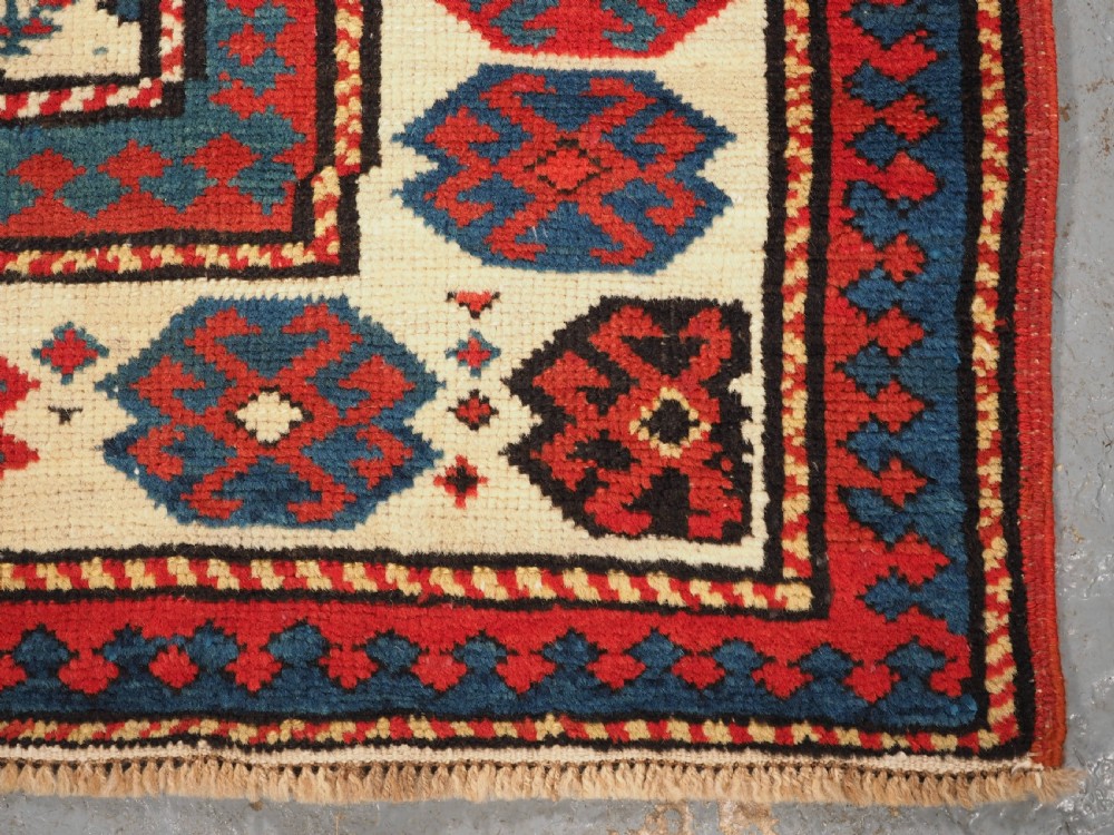 An antique Caucasian Gendje wool runner rug featuring a central field with diagonal stripes in red, blue, and cream surrounded by geometric borders. View XI