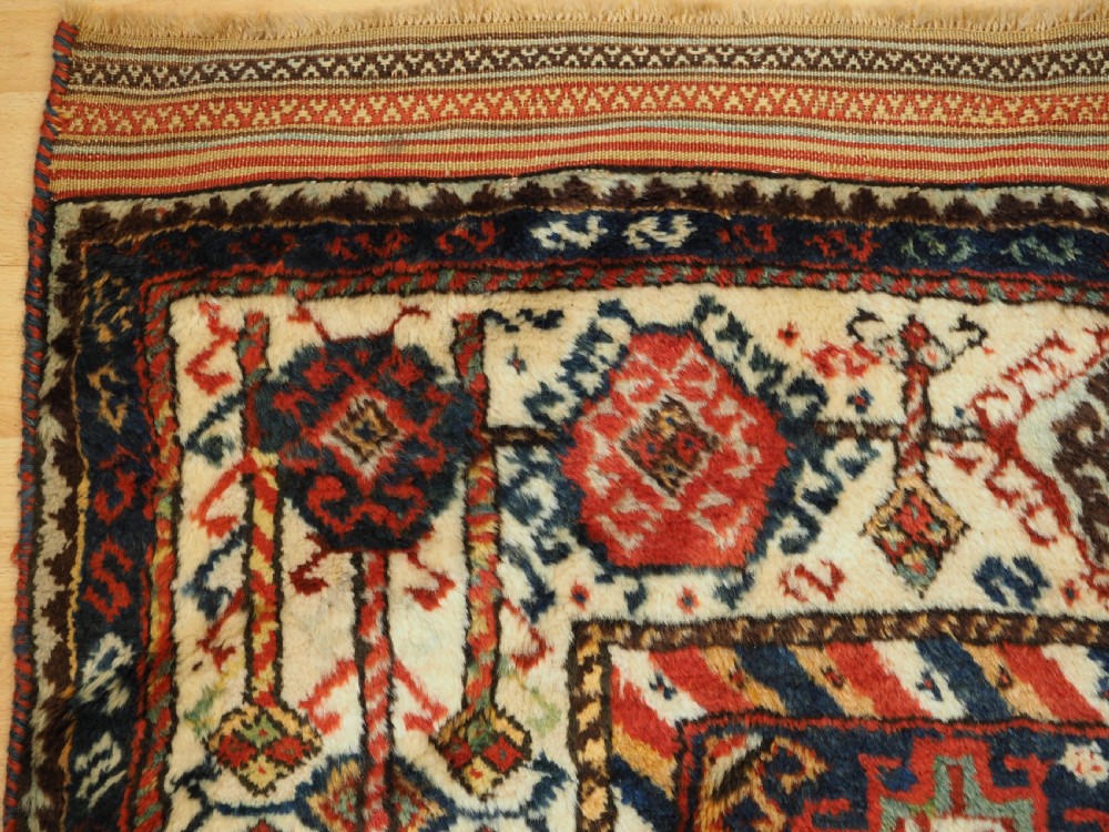 An antique Persian Qashqai Shekarlu wool rug featuring geometric diamond medallions in deep red, navy blue, and cream shades. View XXIII