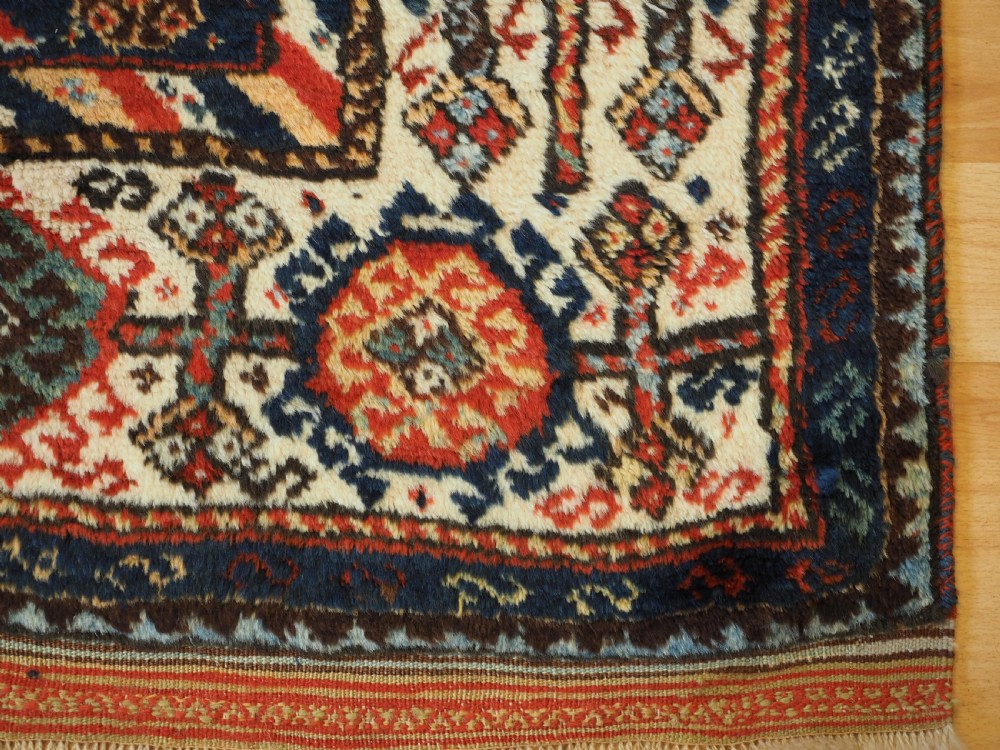 An antique Persian Qashqai Shekarlu wool rug featuring geometric diamond medallions in deep red, navy blue, and cream shades. View XXVII