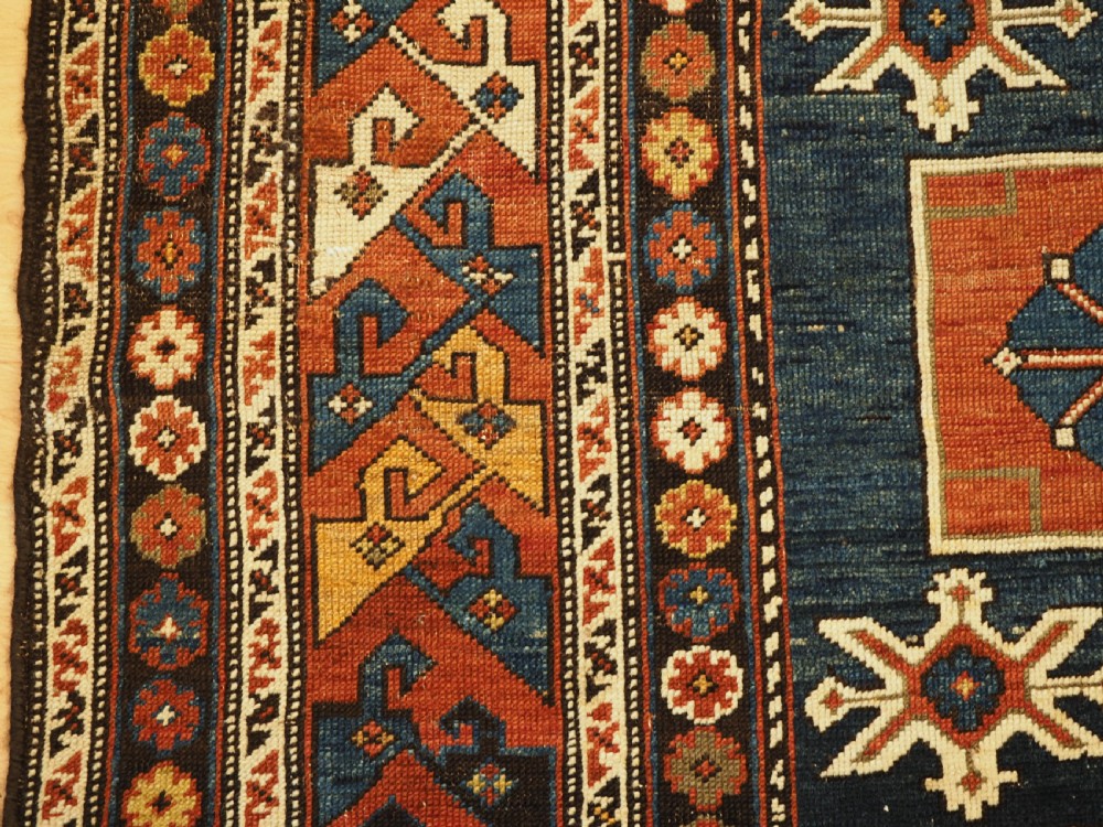 An antique Caucasian Karagashli rug featuring three central square medallions within a dark blue field and geometric borders. View VII