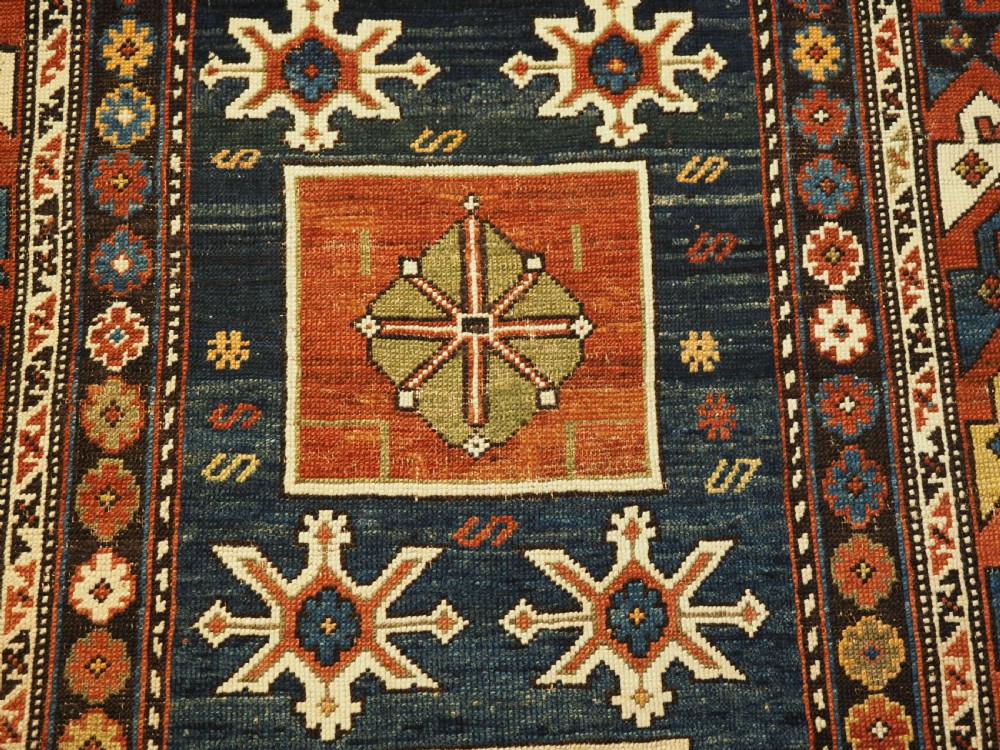 An antique Caucasian Karagashli rug featuring three central square medallions within a dark blue field and geometric borders. View VIII
