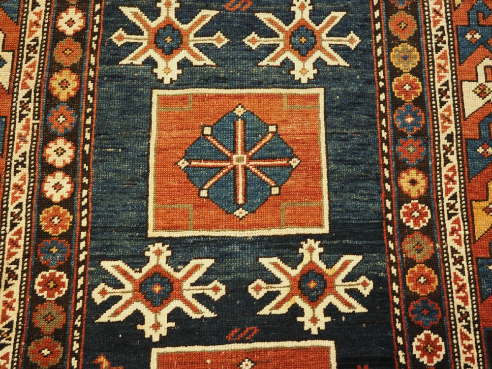 An antique Caucasian Karagashli rug featuring three central square medallions within a dark blue field and geometric borders. View IX