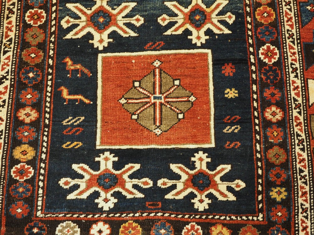 An antique Caucasian Karagashli rug featuring three central square medallions within a dark blue field and geometric borders. View X