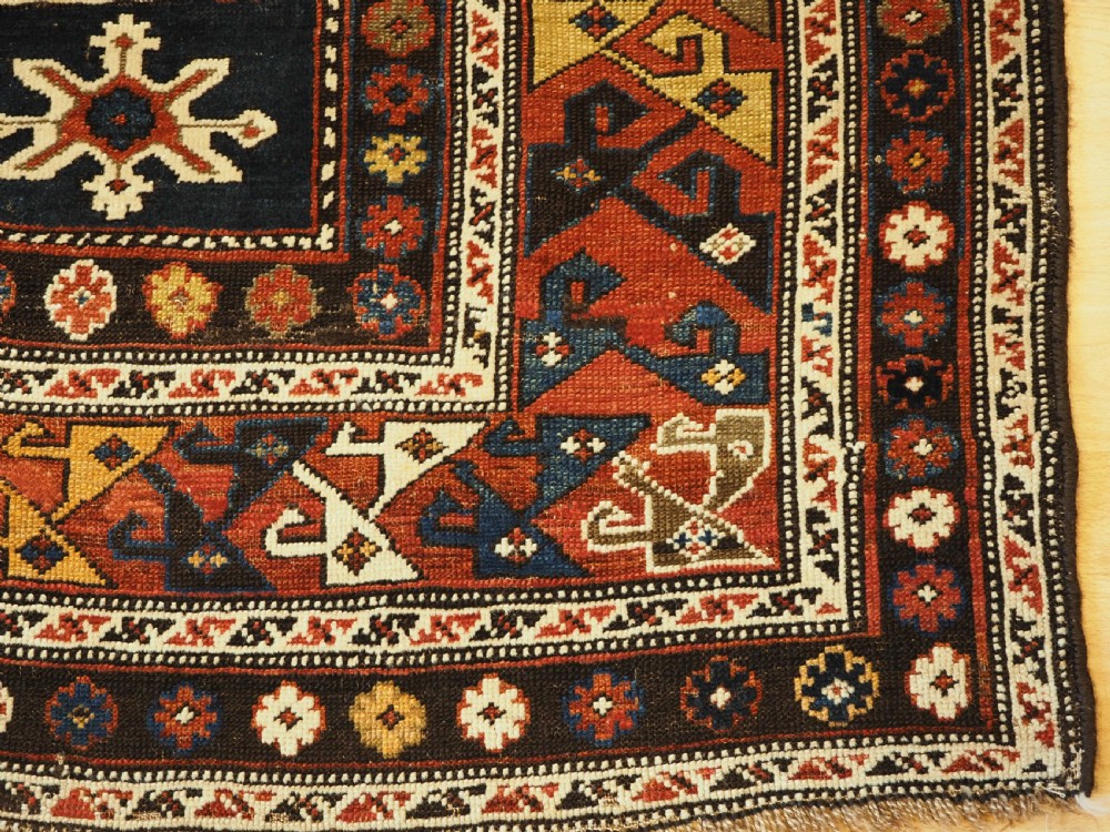 An antique Caucasian Karagashli rug featuring three central square medallions within a dark blue field and geometric borders. View XI