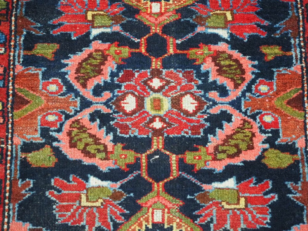 An antique long hand-knotted Persian Hamadan runner rug featuring geometric medallions in shades of dark blue, red, cream, and terracotta. View VI
