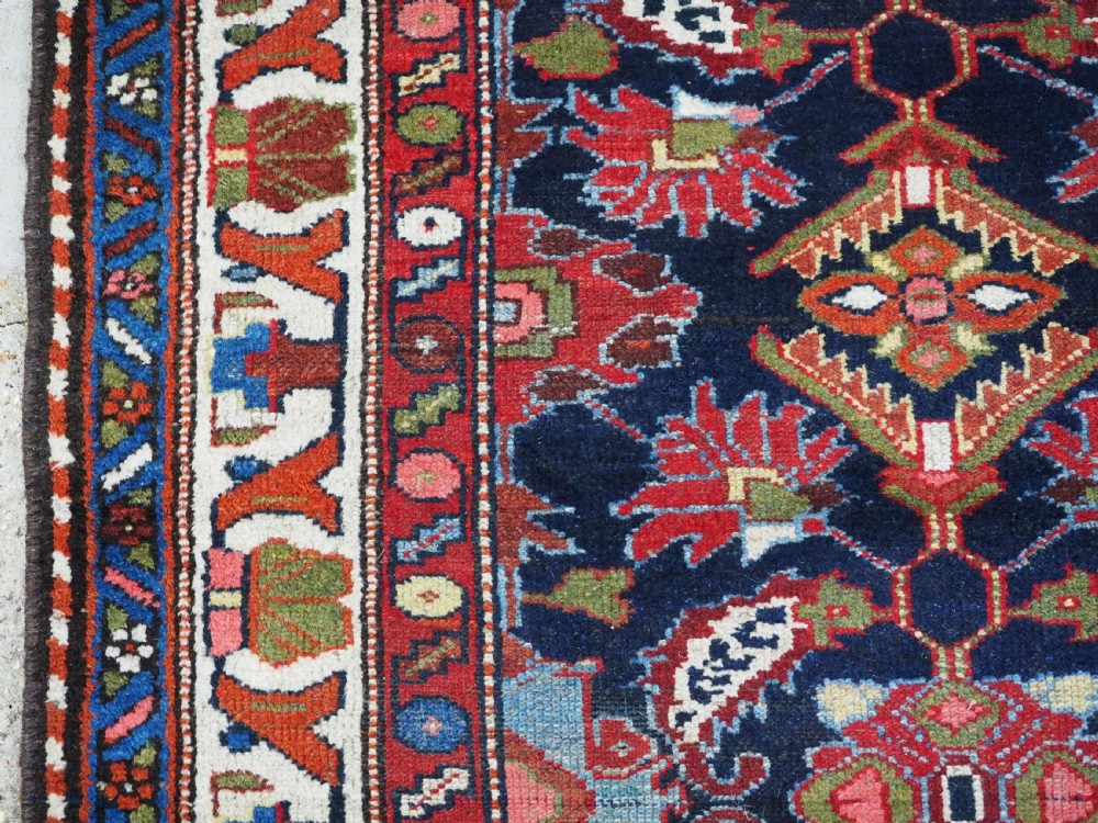An antique long hand-knotted Persian Hamadan runner rug featuring geometric medallions in shades of dark blue, red, cream, and terracotta. View VII