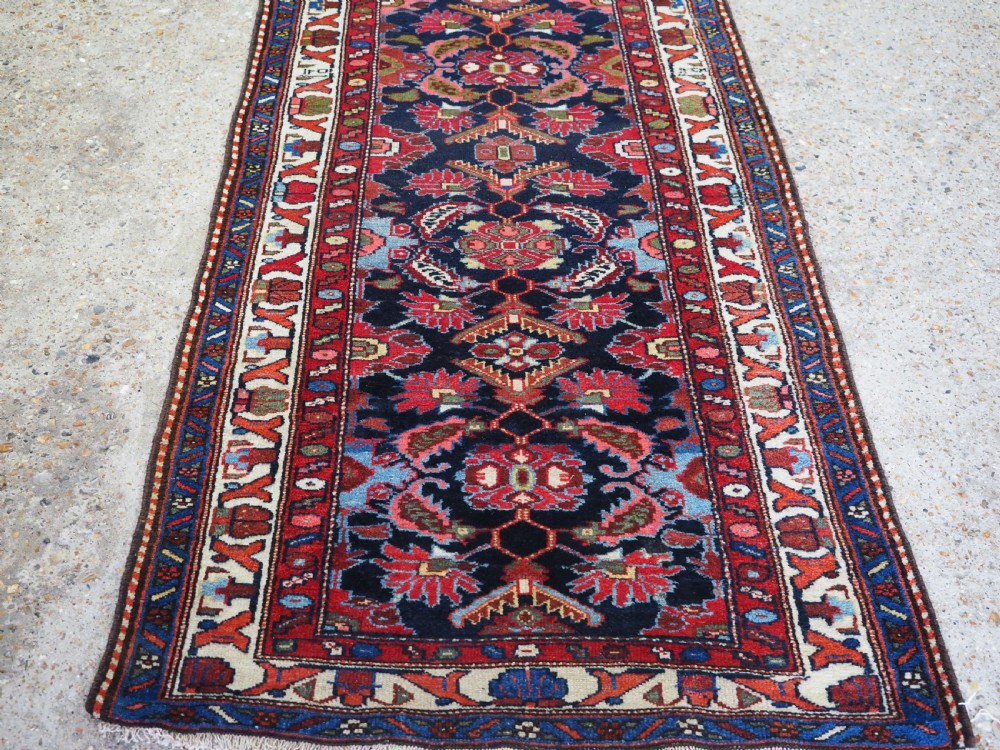 An antique long hand-knotted Persian Hamadan runner rug featuring geometric medallions in shades of dark blue, red, cream, and terracotta. View VIII