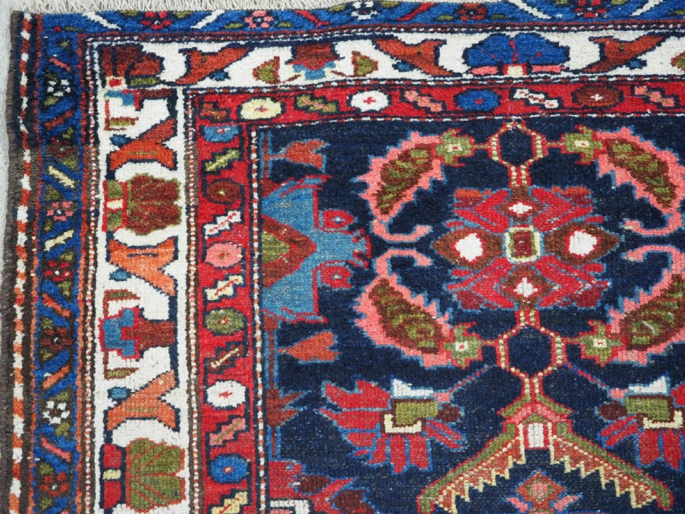 An antique long hand-knotted Persian Hamadan runner rug featuring geometric medallions in shades of dark blue, red, cream, and terracotta. View IX