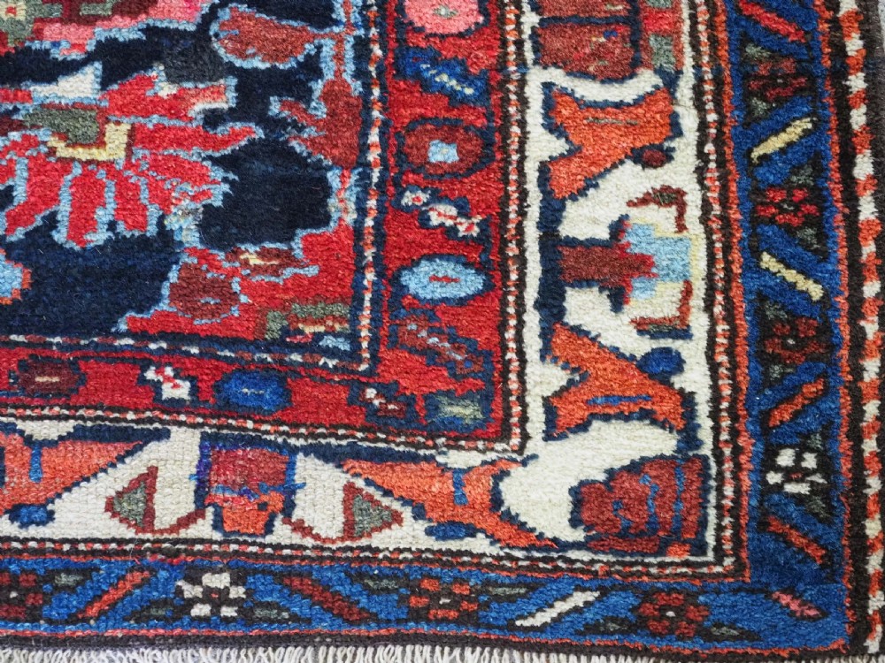 An antique long hand-knotted Persian Hamadan runner rug featuring geometric medallions in shades of dark blue, red, cream, and terracotta. View XI