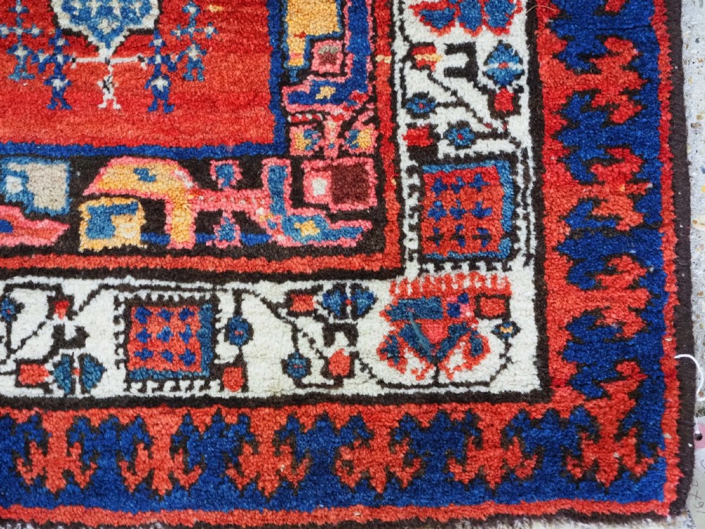 An antique Persian Sarab runner rug featuring repeating geometric diamond medallions on a camel beige central field with terracotta red and navy borders. View X