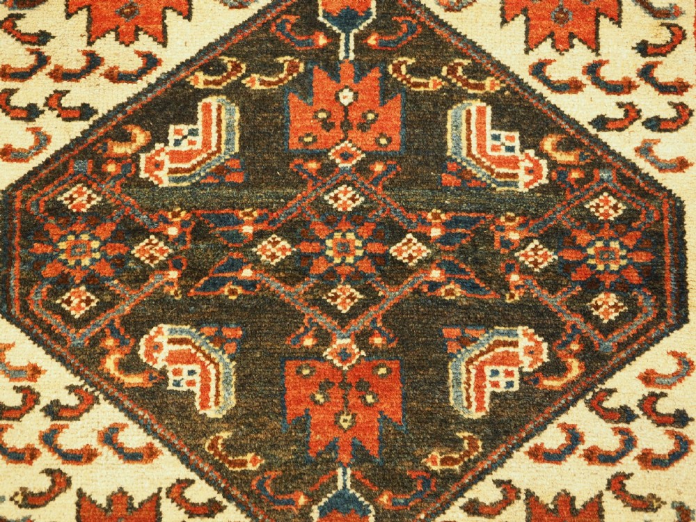 An antique hand-knotted wool rug featuring a central dark blue geometric diamond medallion framed by cream and terracotta field patterns. View VIII