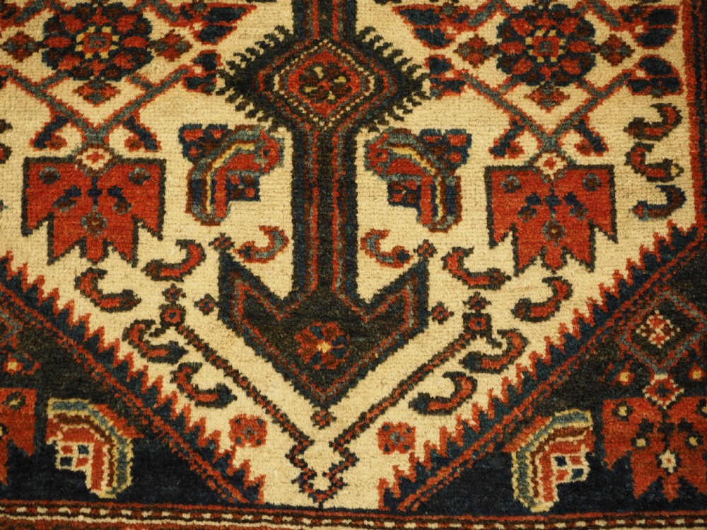 An antique hand-knotted wool rug featuring a central dark blue geometric diamond medallion framed by cream and terracotta field patterns. View IX