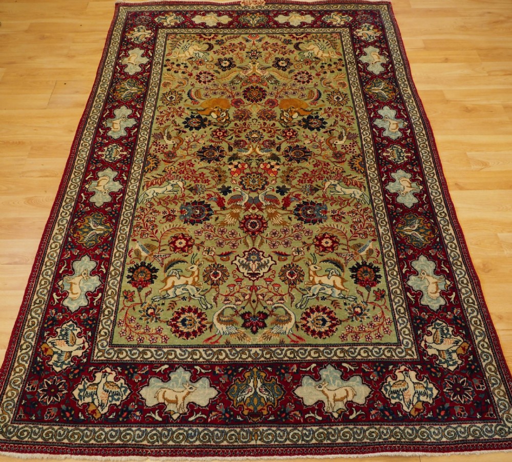 OLD TABRIZ RUG WITH HUNTING DESIGN ON A GREEN GROUND, CIRCA 1930.