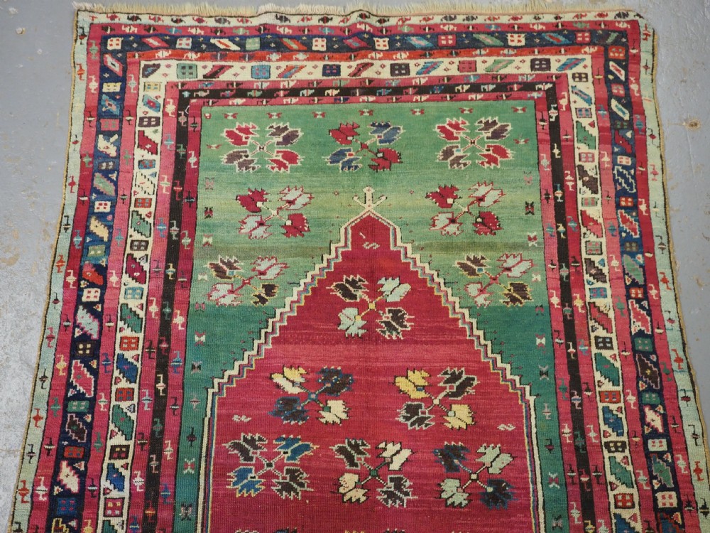 An antique hand-knotted Anatolian Kirsehir prayer rug featuring a central red arch motif framed by green sections and geometric borders. View II