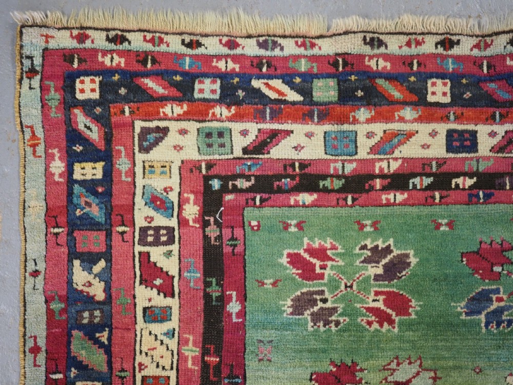 An antique hand-knotted Anatolian Kirsehir prayer rug featuring a central red arch motif framed by green sections and geometric borders. View V