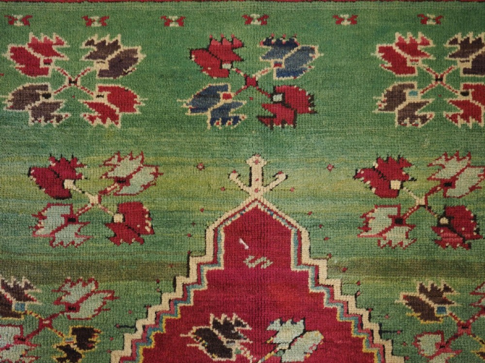 An antique hand-knotted Anatolian Kirsehir prayer rug featuring a central red arch motif framed by green sections and geometric borders. View VI