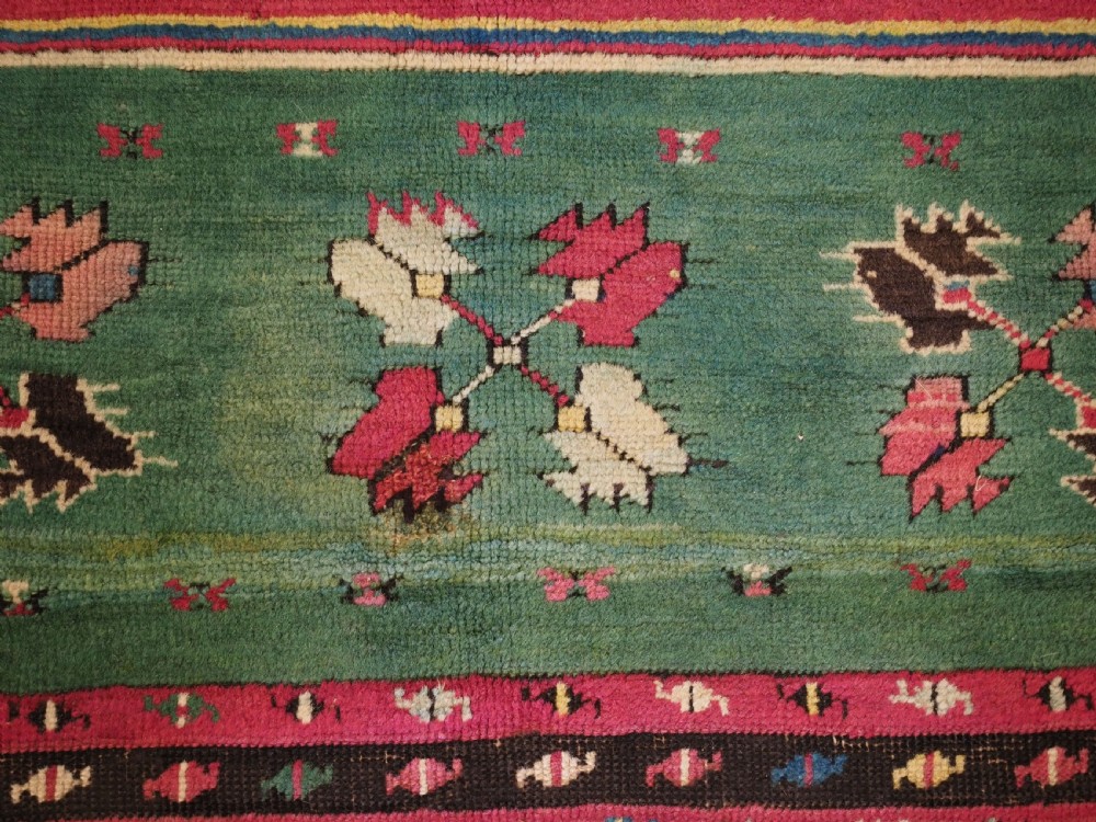 An antique hand-knotted Anatolian Kirsehir prayer rug featuring a central red arch motif framed by green sections and geometric borders. View IX