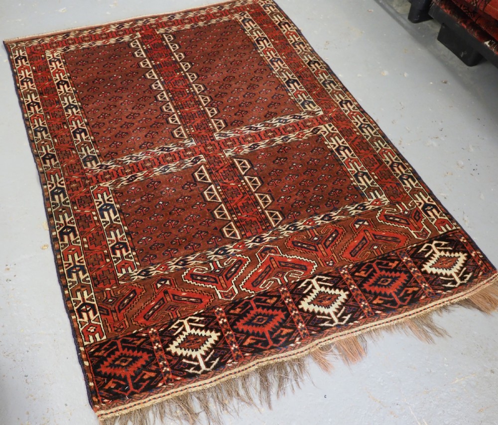 An antique Yomut Turkmen Ensi wool rug featuring a four-part central field design, geometric borders, and an elem end panel in deep red, brown, and ivory. View II
