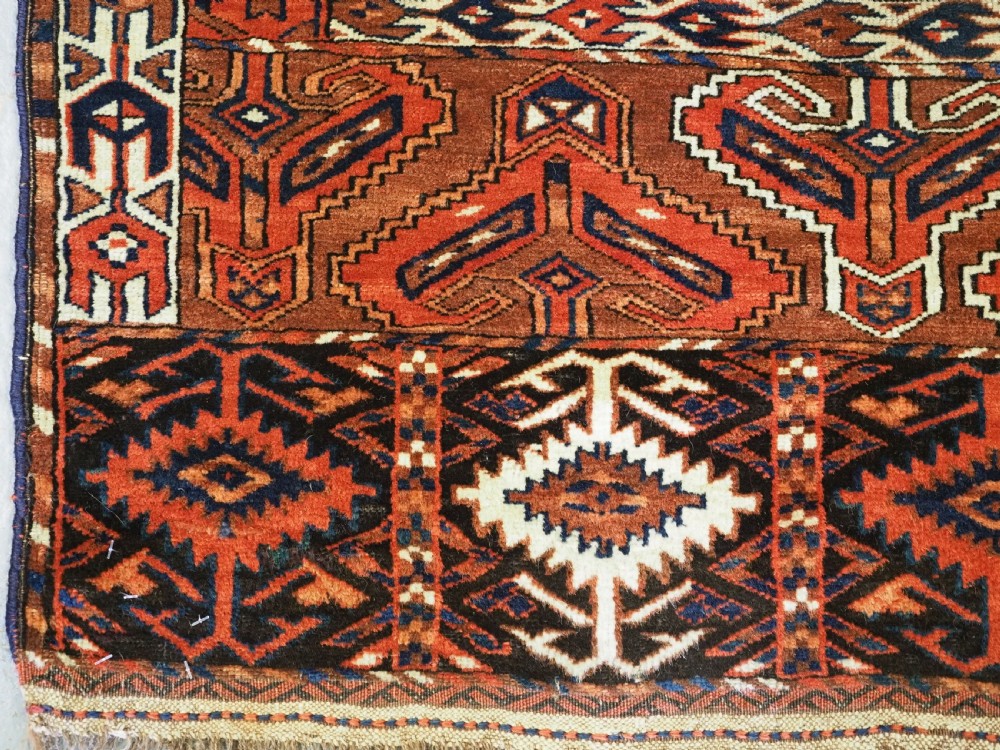 An antique Yomut Turkmen Ensi wool rug featuring a four-part central field design, geometric borders, and an elem end panel in deep red, brown, and ivory. View IX