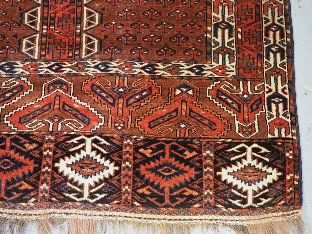 An antique Yomut Turkmen Ensi wool rug featuring a four-part central field design, geometric borders, and an elem end panel in deep red, brown, and ivory. View XII