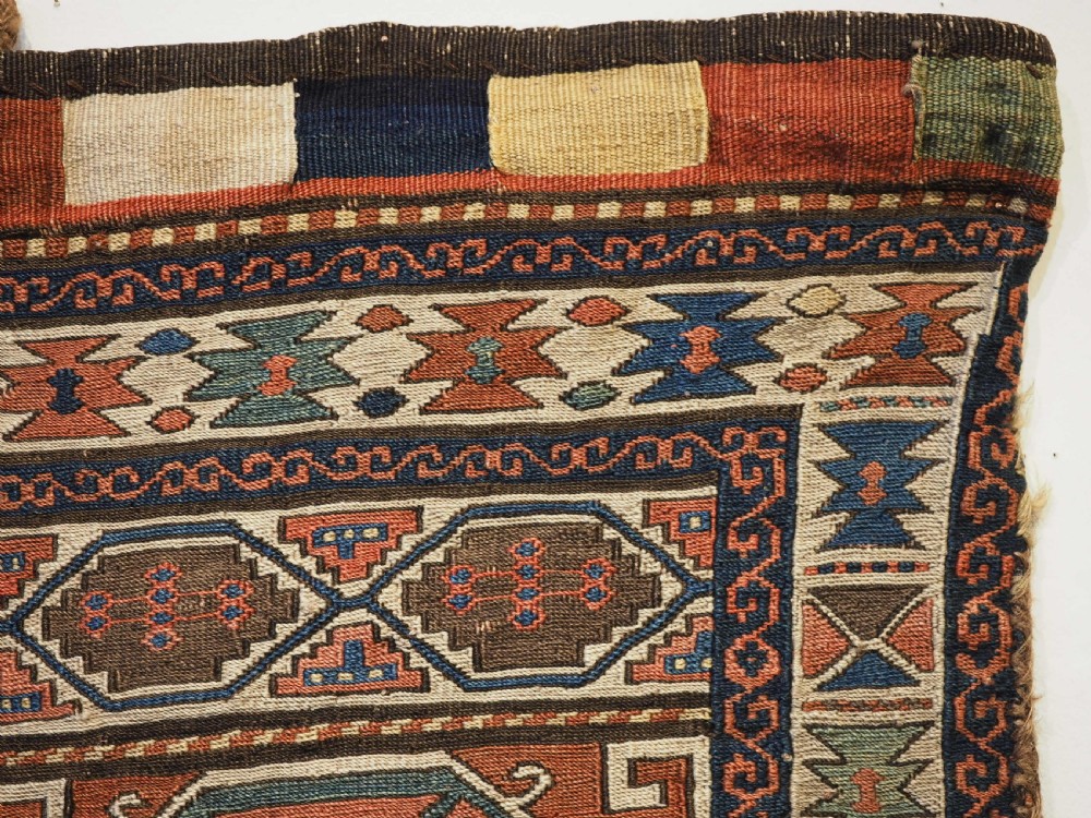 An antique flatwoven wool Shahsavan khorjin bag face featuring geometric octagonal medallions and running dog borders in terracotta red, indigo blue, cream, and sage green. View III