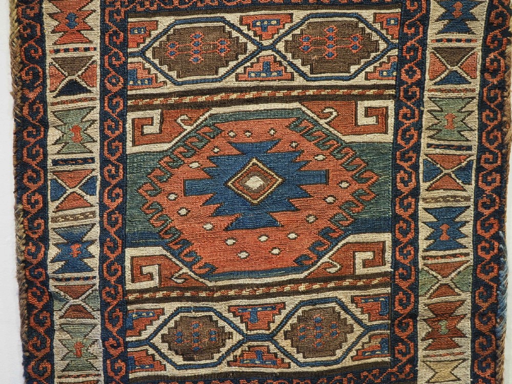 An antique flatwoven wool Shahsavan khorjin bag face featuring geometric octagonal medallions and running dog borders in terracotta red, indigo blue, cream, and sage green. View IV