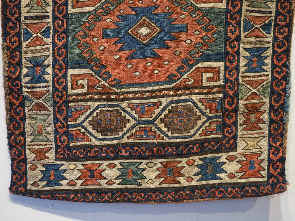 An antique flatwoven wool Shahsavan khorjin bag face featuring geometric octagonal medallions and running dog borders in terracotta red, indigo blue, cream, and sage green. View V