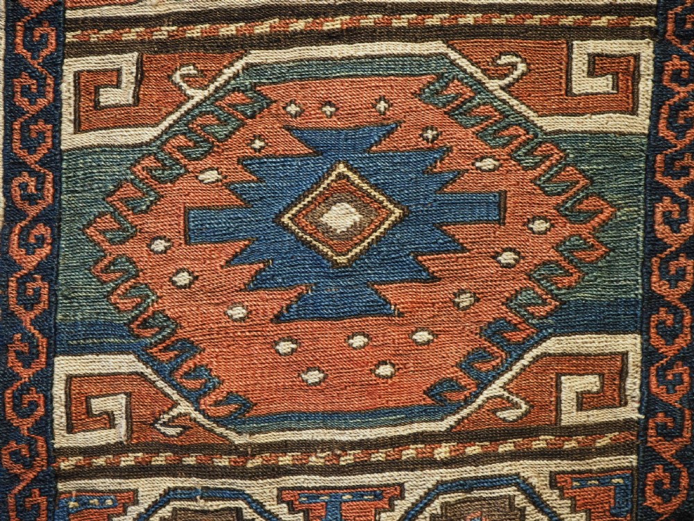 An antique flatwoven wool Shahsavan khorjin bag face featuring geometric octagonal medallions and running dog borders in terracotta red, indigo blue, cream, and sage green. View VI