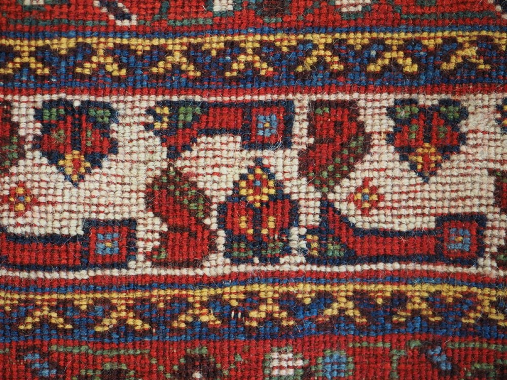 A hand-knotted wool rug featuring three diamond medallions on a dark navy field surrounded by geometric floral borders in red, ivory, and blue. View VIII
