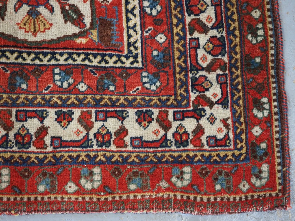 A hand-knotted wool rug featuring three diamond medallions on a dark navy field surrounded by geometric floral borders in red, ivory, and blue. View XV