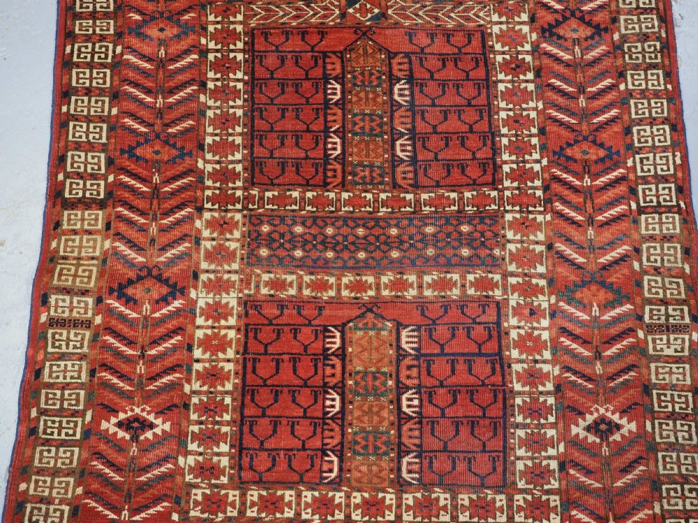 A hand-knotted wool Tekke Turkmen Ensi rug featuring a terracotta red field divided into four panels with dark geometric motifs and intricate borders. View IV