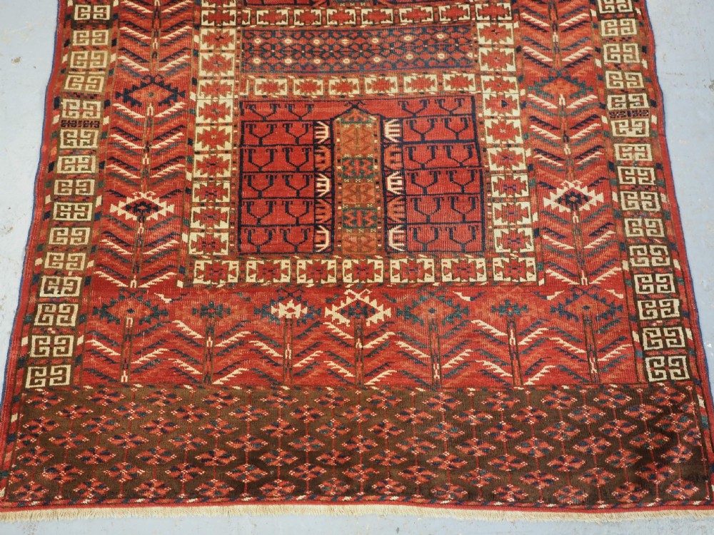 A hand-knotted wool Tekke Turkmen Ensi rug featuring a terracotta red field divided into four panels with dark geometric motifs and intricate borders. View V