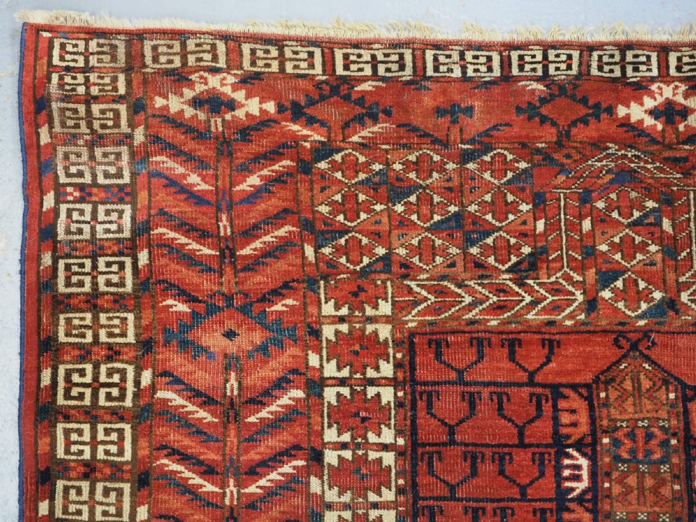 A hand-knotted wool Tekke Turkmen Ensi rug featuring a terracotta red field divided into four panels with dark geometric motifs and intricate borders. View VI