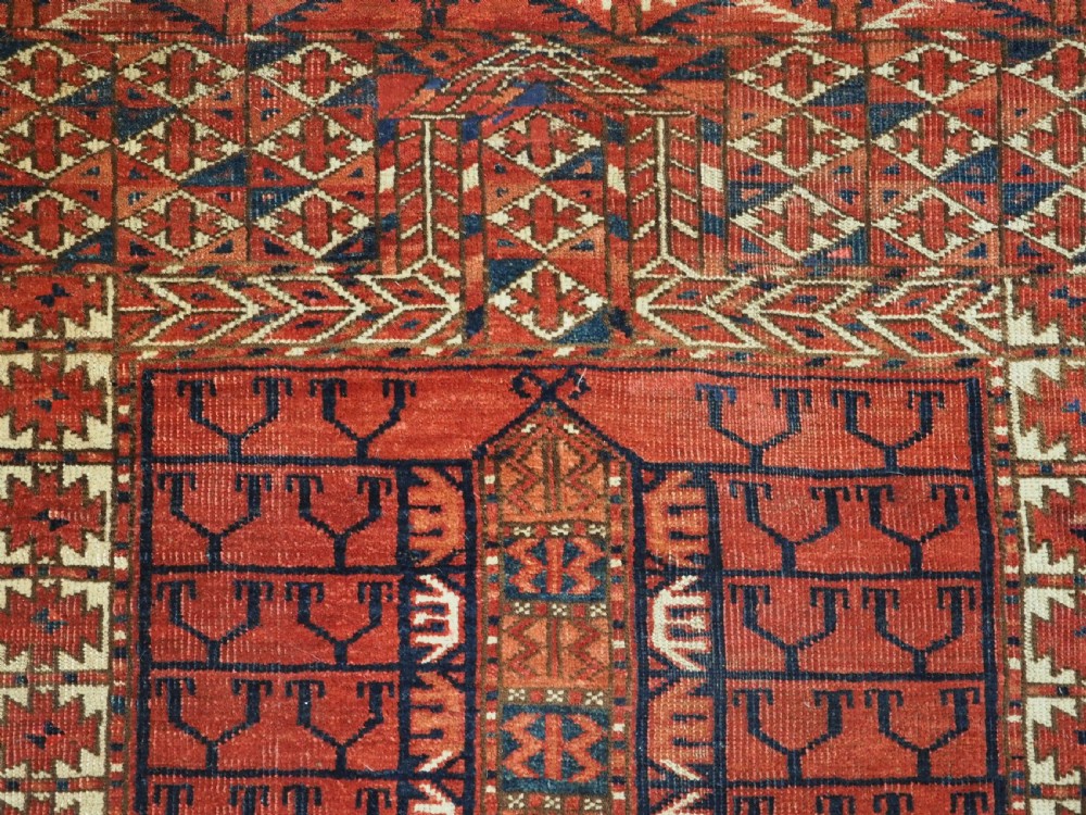 A hand-knotted wool Tekke Turkmen Ensi rug featuring a terracotta red field divided into four panels with dark geometric motifs and intricate borders. View VII