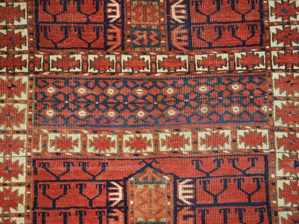 A hand-knotted wool Tekke Turkmen Ensi rug featuring a terracotta red field divided into four panels with dark geometric motifs and intricate borders. View VIII