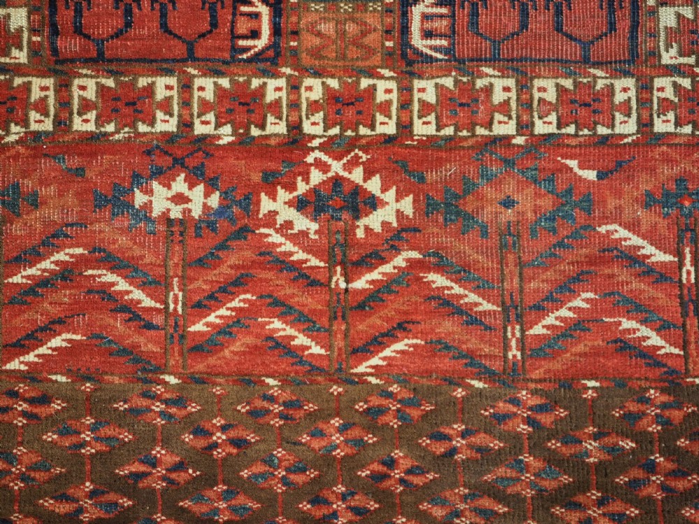 A hand-knotted wool Tekke Turkmen Ensi rug featuring a terracotta red field divided into four panels with dark geometric motifs and intricate borders. View IX