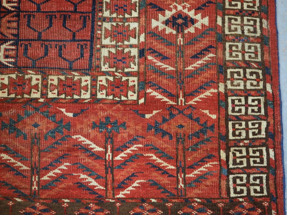 A hand-knotted wool Tekke Turkmen Ensi rug featuring a terracotta red field divided into four panels with dark geometric motifs and intricate borders. View X