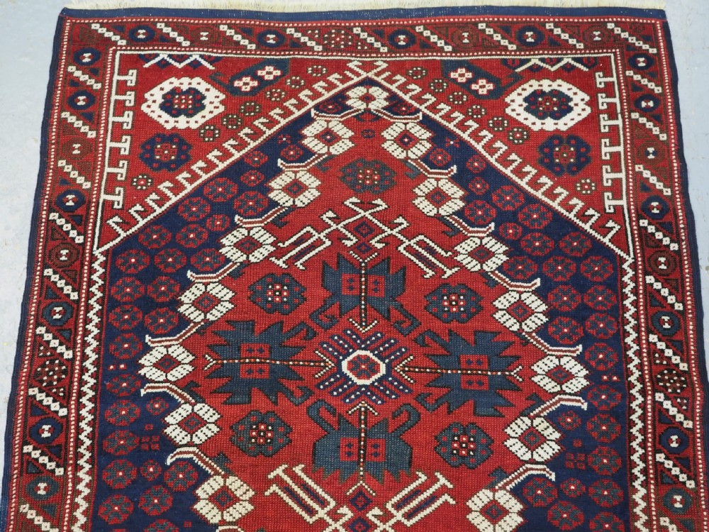 An antique hand-knotted Turkish Kiz Bergama wool rug featuring a red field, central diamond medallion, navy blue accents, and geometric borders. View III