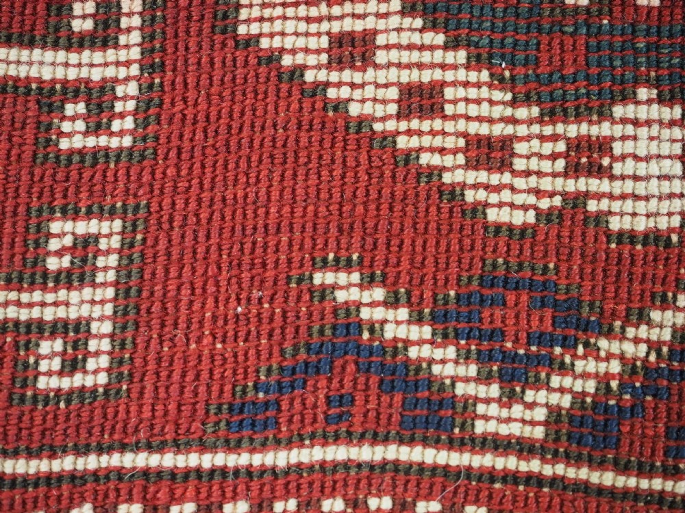An antique hand-knotted Turkish Kiz Bergama wool rug featuring a red field, central diamond medallion, navy blue accents, and geometric borders. View VII
