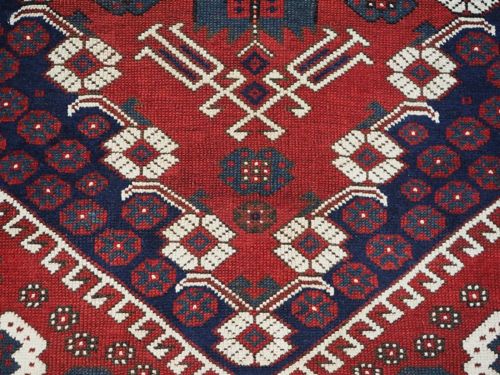 An antique hand-knotted Turkish Kiz Bergama wool rug featuring a red field, central diamond medallion, navy blue accents, and geometric borders. View VIII