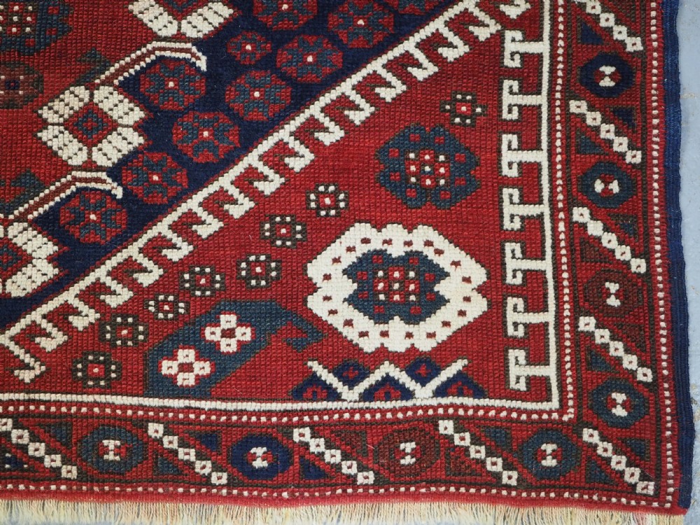 An antique hand-knotted Turkish Kiz Bergama wool rug featuring a red field, central diamond medallion, navy blue accents, and geometric borders. View X