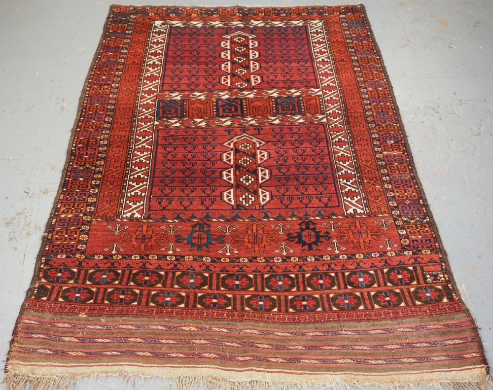 An antique hand-knotted Ersari Turkmen Ensi wool rug featuring deep red tones, a central cruciform design, geometric borders, and a woven fringe.
