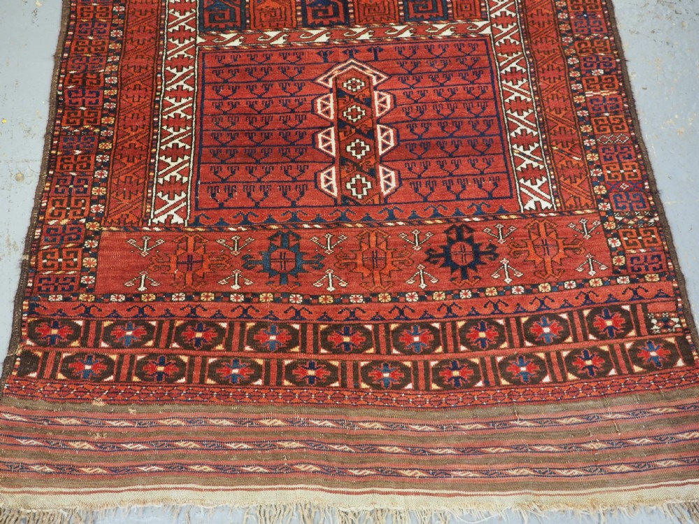 An antique hand-knotted Ersari Turkmen Ensi wool rug featuring deep red tones, a central cruciform design, geometric borders, and a woven fringe. View V