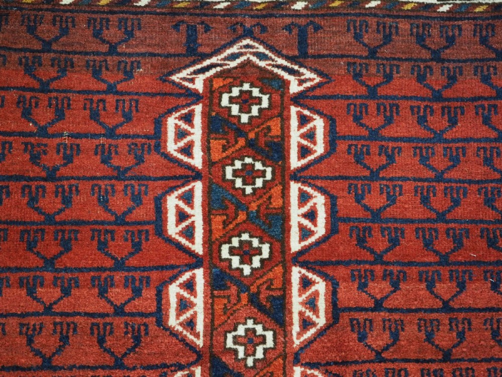 An antique hand-knotted Ersari Turkmen Ensi wool rug featuring deep red tones, a central cruciform design, geometric borders, and a woven fringe. View VII