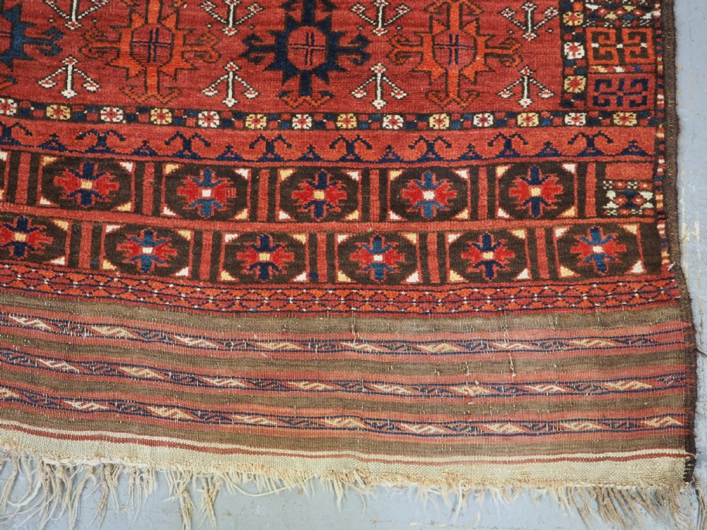 An antique hand-knotted Ersari Turkmen Ensi wool rug featuring deep red tones, a central cruciform design, geometric borders, and a woven fringe. View XII
