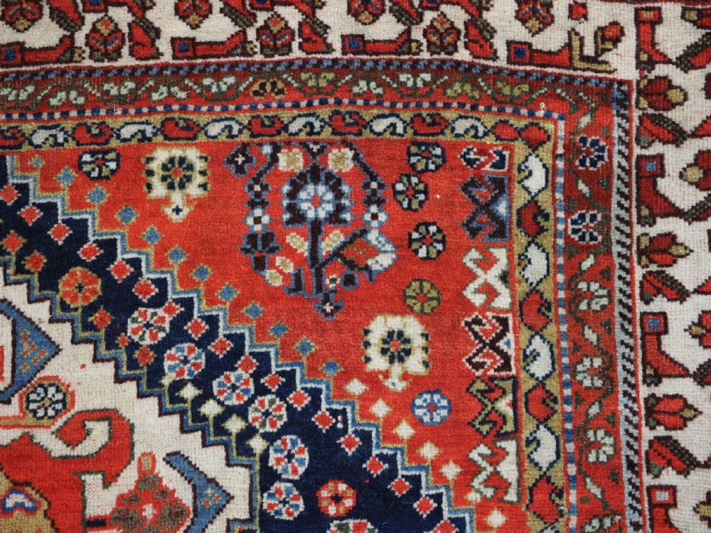 An antique hand-knotted Qashqai wool rug featuring a navy blue field with stacked diamond medallions surrounded by terracotta red borders and tribal geometric motifs. View XIII