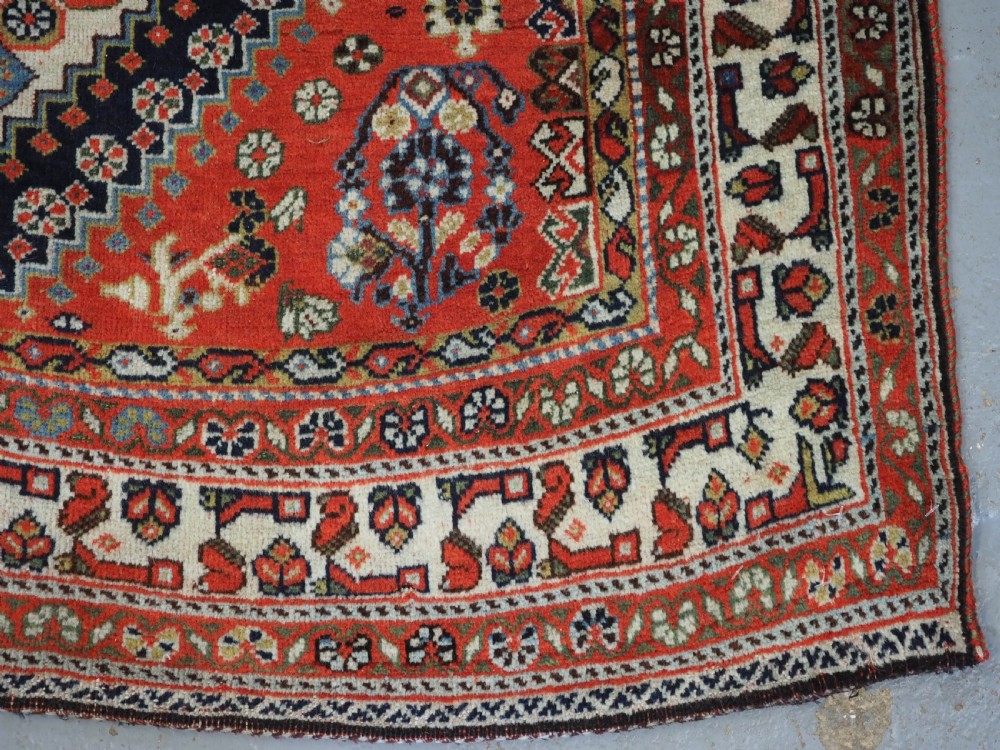 An antique hand-knotted Qashqai wool rug featuring a navy blue field with stacked diamond medallions surrounded by terracotta red borders and tribal geometric motifs. View XIV