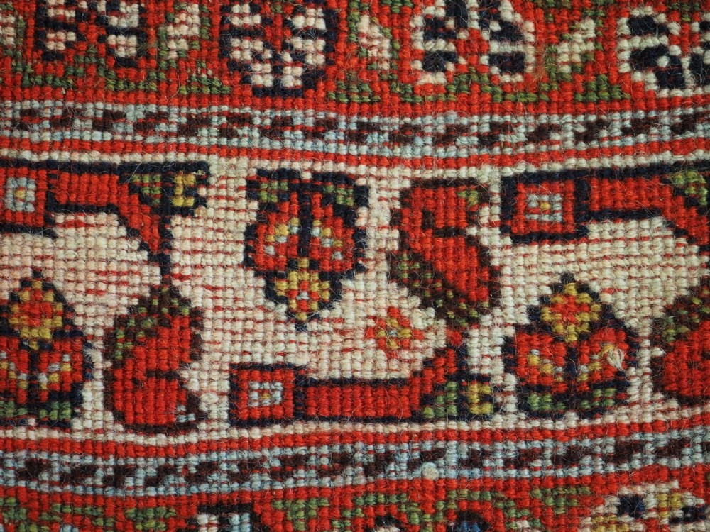 An antique hand-knotted Qashqai wool rug featuring a navy blue field with stacked diamond medallions surrounded by terracotta red borders and tribal geometric motifs. View XV